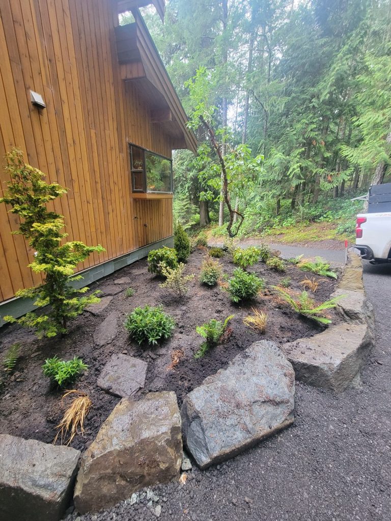 New boulder-edged bed beside a cedar house