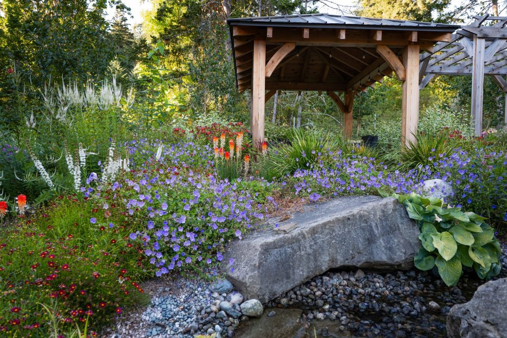 Gazebo above a stone bridge with geraniums and red-hot pokers